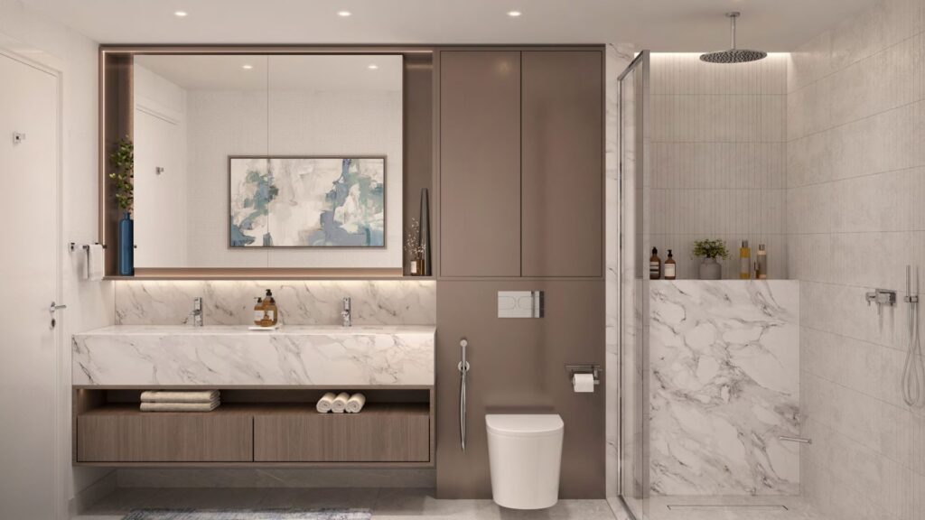 Salle de bains moderne avec double lavabo en marbre, grand miroir, toilettes murales et douche en verre à Windsor House de Ellington Properties. Des objets d'art décoratifs et des articles de toilette sont soigneusement disposés sur les armoires et les étagères aux tons neutres.