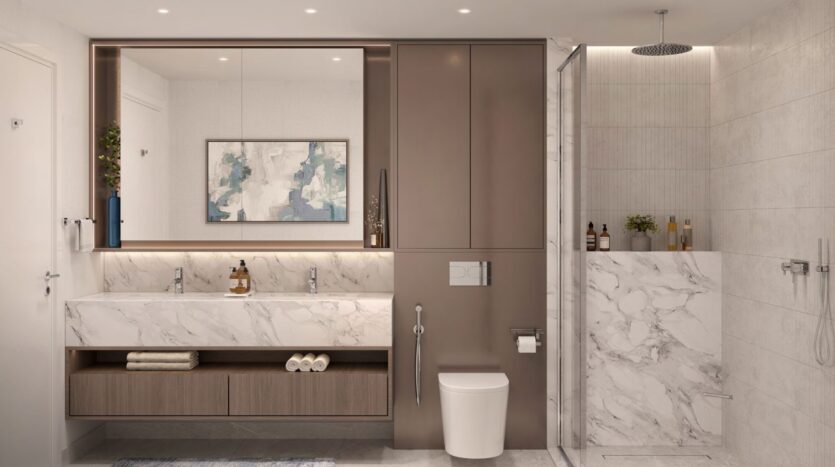 Salle de bains moderne avec double lavabo en marbre, grand miroir, toilettes murales et douche en verre à Windsor House de Ellington Properties. Des objets d'art décoratifs et des articles de toilette sont soigneusement disposés sur les armoires et les étagères aux tons neutres.