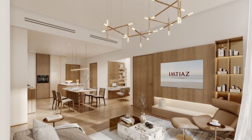 Un salon et une salle à manger modernes et ouverts au Wynwood Horizon de Imtiaz, avec des sols en bois, des meubles neutres, des lustres dorés, une télévision murale affichant "IMTIAZ" et une décoration minimaliste élégante.