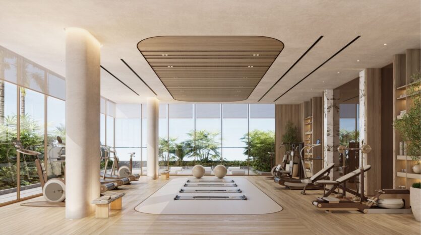 Cette salle de sport moderne située à Wynwood Horizon de Imtiaz est dotée de grandes fenêtres, de planchers en bois clair, de réformateurs de pilates, de ballons de gymnastique et de machines d'exercice. Lumineuse et minimaliste, elle offre des accents naturels avec une verdure luxuriante visible à l'extérieur.
