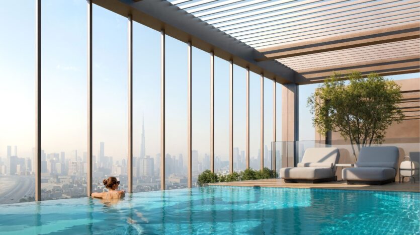 Une personne nage dans la piscine à débordement de Wynwood Horizon de Imtiaz, profitant des chaises longues sur le toit, des arbres et de l'horizon dégagé de la ville sous une pergola moderne.