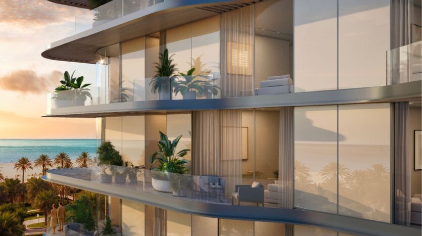 Avida Residences Dubai Islands offers modern luxury apartments with large glass balconies, potted plants and outdoor seating overlooking palm trees and the ocean at sunset, creating a serene and elegant atmosphere.