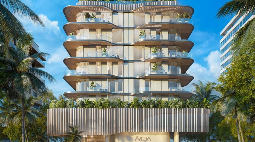 Modern multi-storey building with curved balconies and glass railings, surrounded by palm trees. Avida Residences Dubai Islands features greenery on every balcony and a sleek, contemporary design against a backdrop of bright blue skies.