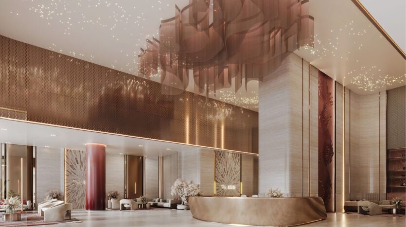 El lujoso vestíbulo del hotel presenta techos altos, una elegante decoración en dorado y crema, una escultural lámpara de araña, un moderno mostrador de recepción, asientos de felpa y grandes pilares, que reflejan el sofisticado ambiente del emblemático diseño del Binghatti Skyblade.