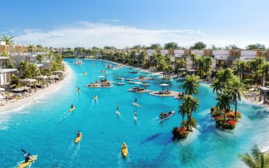 Die große hellblaue Lagune von Damac Islands 2 ist von modernen Villen, Palmen und Sandstränden umgeben, wo die Menschen unter einem strahlend blauen Himmel Kajak und Paddleboard fahren und auf schwimmenden Plattformen entspannen.