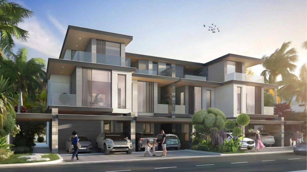 Modern three-storey houses with large windows, balconies and carports define Damac Islands 2. Many people, including children and adults, enjoy the outdoors amid palm trees and lush greenery, with cars parked in the driveways.