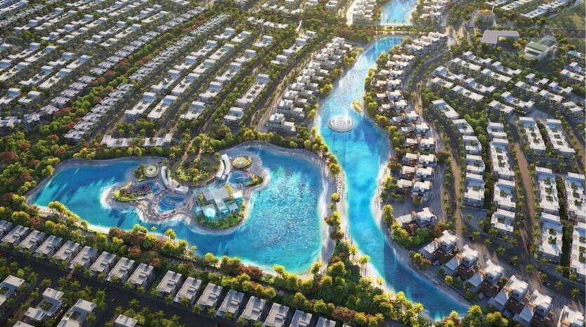 Aerial view of Damac Islands 2, a large residential community featuring winding canals of blue water, a central lagoon with an island, and rows of modern homes surrounded by greenery.