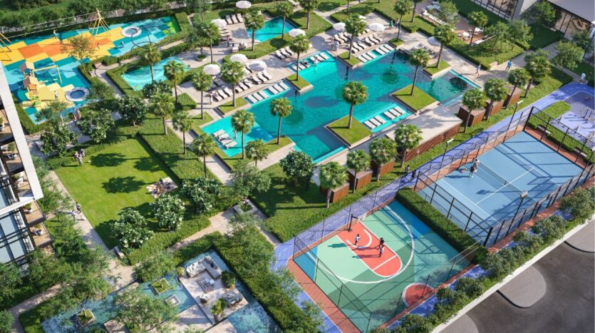 Vue aérienne de l'aire de loisirs extérieure moderne de Sierra by Iman avec des piscines, des chaises longues, des palmiers, une aire de jeux colorée, des terrains de basket et de tennis clôturés, le tout entouré de jardins paysagers et de sentiers de promenade.