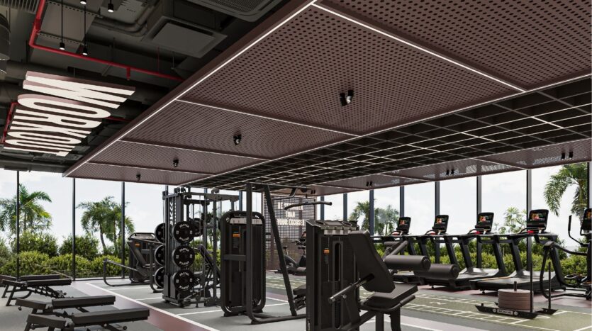 Salle de sport moderne avec des machines de musculation, des tapis de course et un panneau "WORKOUT" au plafond. De grandes fenêtres laissent apparaître des palmiers et de la verdure, créant une atmosphère lumineuse et accueillante au Sierra by Iman.