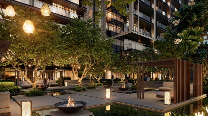 La cour d'un appartement moderne au crépuscule chez Sierra by Iman se compose d'arbres luxuriants, d'une pergola confortable, de lanternes lumineuses, de foyers et d'un étang réfléchissant, créant ainsi un espace extérieur chaleureux et accueillant.