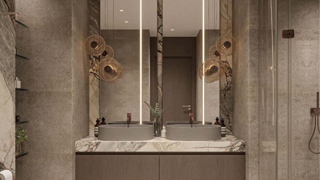 Salle de bains moderne avec double lavabo, comptoir en marbre et grands miroirs éclairés. Des lampes suspendues de la collection Sierra by Iman sont suspendues au-dessus des lavabos, complétant les portes de douche en verre et le design épuré et contemporain dans des tons neutres.
