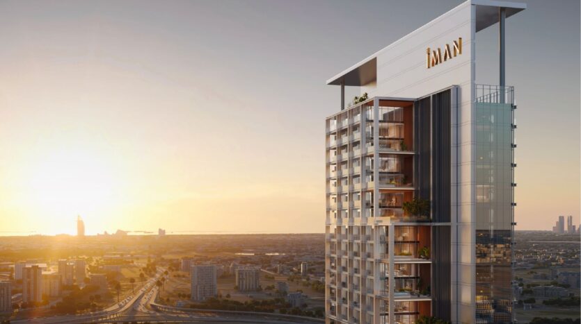Une tour moderne avec des balcons en verre et des enseignes "IMAN" se dresse au coucher du soleil, surplombant un paysage urbain tentaculaire - c'est Sierra by IMAN, qui redéfinit l'habitat de luxe sur une ligne d'horizon urbaine époustouflante.