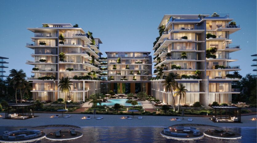 Immeubles d'appartements modernes au bord de l'eau, de nuit, sur les îles Silena Dubai, avec des balcons illuminés, une végétation luxuriante, des palmiers et une piscine centrale. Des foyers et des places assises bordent le rivage, reflétant le luxe et la tranquillité.