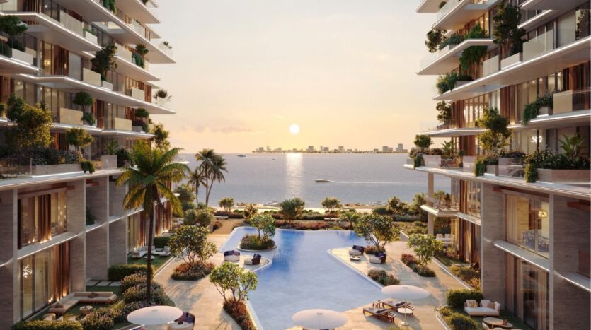 Les appartements de luxe Silena Dubai Islands en bord de mer donnent sur une grande piscine entourée de palmiers et de chaises longues, offrant une vue à couper le souffle sur l'océan calme et la ligne d'horizon de la ville au coucher du soleil.