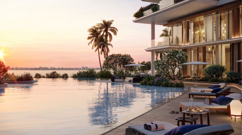 Une piscine luxueuse au coucher du soleil sur les îles Silena de Dubaï, avec des chaises longues, des parasols, des plantes tropicales luxuriantes et un bâtiment moderne surplombant l'eau calme et l'horizon lointain de la ville.