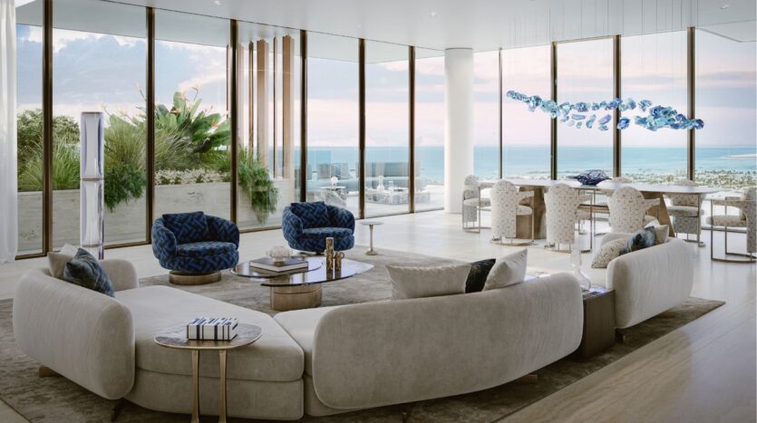 Le salon et la salle à manger modernes et ouverts du Silena Dubai Islands, avec de grandes fenêtres allant du sol au plafond, des meubles neutres, des fauteuils bleus, un lustre sculptural et une vue imprenable sur l'océan en arrière-plan.