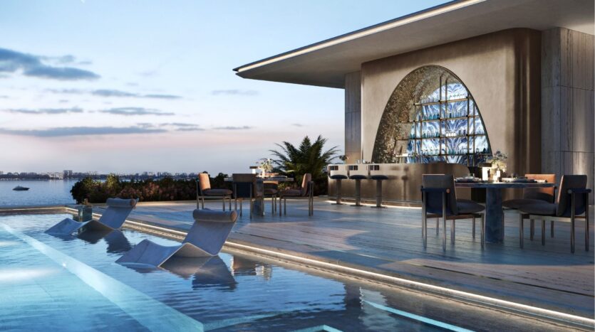 Au coucher du soleil, la piscine luxueuse offre des chaises longues immergées, des tables élégantes, des sièges de bar modernes et une vue pittoresque sur le front de mer, avec des eaux calmes et un ciel légèrement éclairé, au Silena Dubai Islands.