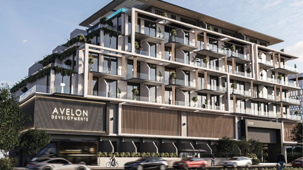 Immeuble d'appartements moderne de plusieurs étages avec de grands balcons, des garde-corps en verre et de la verdure à chaque niveau. L'enseigne indique "Avelon Developments". Des voitures et un bus passent devant l'immeuble.