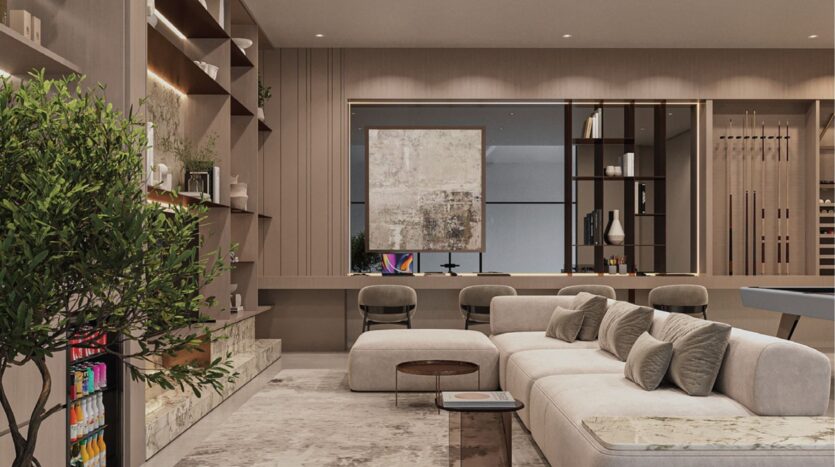 Salon moderne avec un canapé sectionnel beige, une table basse, des étagères encastrées, une plante en pot et un espace de travail avec deux chaises et une œuvre d'art abstraite au mur. Les tons neutres et chauds et l'éclairage doux créent une atmosphère chaleureuse.