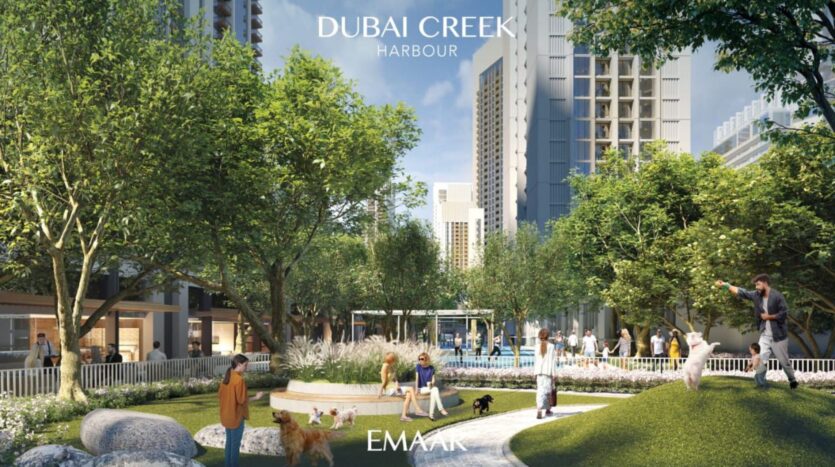 Persone e cani si godono un parco verde circondato da alti edifici moderni nel Dubai Creek Harbour, vicino al Lyvia by Palace Residence. Alberi, camminamenti e panchine creano un vivace spazio urbano all'aperto, con i loghi EMAAR e Dubai Creek Harbour ben visibili.