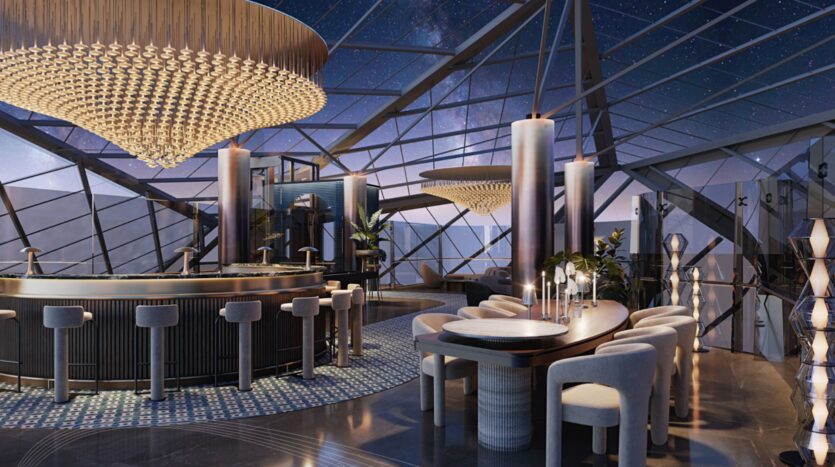 Ce salon moderne et élégant situé au Portside Square Mina Rashid est doté de murs et d'un plafond en verre allant du sol au plafond et offrant une vue sur la nuit étoilée. Des sièges en peluche, un bar circulaire, de grands lustres et un décor géométrique créent une ambiance luxueuse.