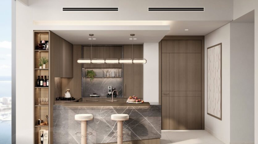 La cuisine moderne de Portside Square Mina Rashid se compose d'armoires en bois clair, d'un îlot en marbre avec tabourets, d'étagères encastrées pour la décoration et le vin, d'appareils électroménagers élégants, d'une grande fenêtre donnant sur l'eau, d'un éclairage minimaliste et d'œuvres d'art murales abstraites.