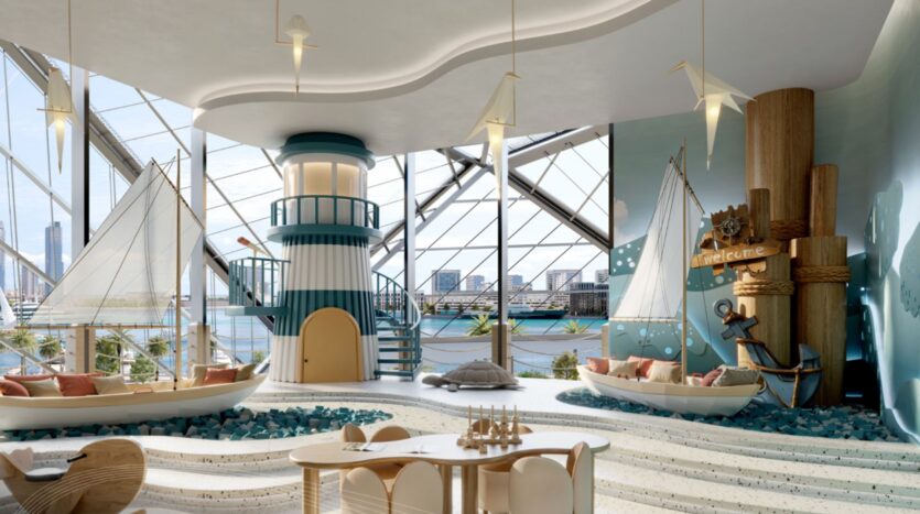 La salle de jeux pour enfants de Portside Square Mina Rashid, lumineuse et au thème nautique, comprend des lits en forme de voilier, un grand phare intérieur, des décorations sur le thème de la mer et de grandes fenêtres donnant sur un paysage urbain au bord de l'eau.