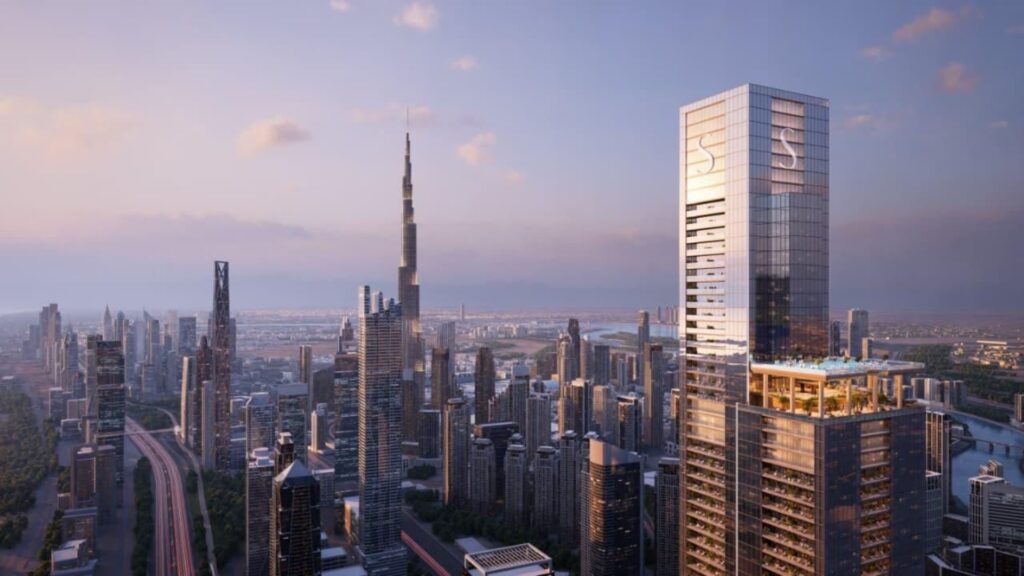 A city skyline at sunset features many modern skyscrapers. The tallest building, the Burj Khalifa, stands among other skyscrapers and SkyParks nestled atop the rooftops. The sky shines with a soft, warm glow and a few clouds drift by.