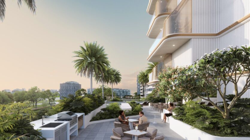 Una moderna terrazza all'aperto presso il Sunset Bay Grand Residence di Imtiaz a Dubai Islands, con persone sedute ai tavoli in mezzo al verde e alle palme accanto a un edificio contemporaneo con balconi curvi; la vista sulla città incornicia il cielo limpido.
