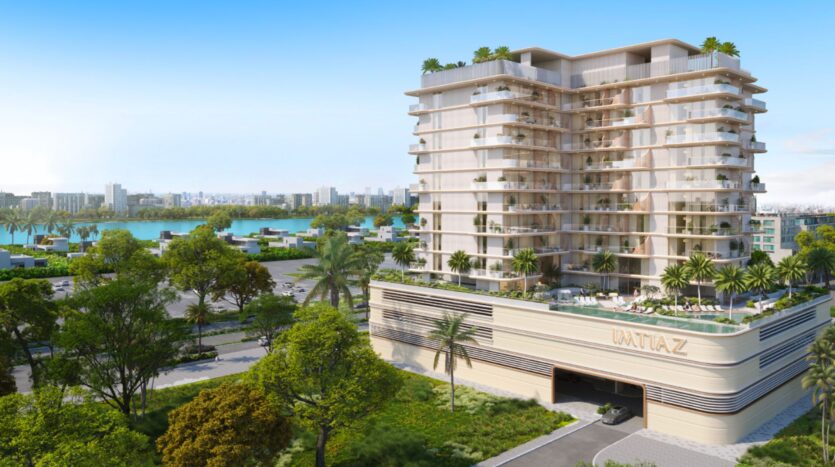 Il Sunset Bay Grand Residence di Imtiaz a Dubai Islands, un moderno edificio a più piani con ampi balconi, circondato da palme e verde, offre una vista sulla città e sul lungomare sotto un cielo azzurro e limpido.