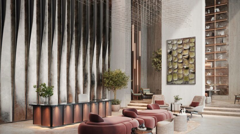 La moderna hall dell'hotel Residence Sunset Bay Grand di Imtiaz a Dubai Islands è caratterizzata da soffitti alti, pannelli metallici ondulati alle pareti, sedute rosse di peluche, alberi in vaso, un grande dipinto astratto e un'alta mensola che espone oggetti decorativi.