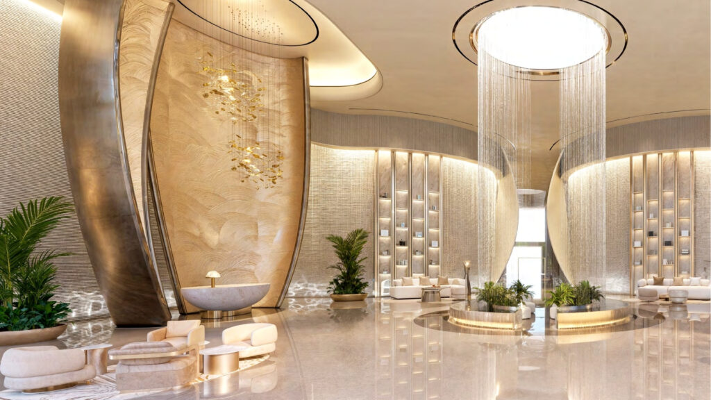 Luxurious lobby with high ceilings, elegant gold and beige décor, curved wall elements, modern seating and lush green plants, reflecting the sophisticated ambience of Breez by Danube Maritime City. A large circular chandelier serves as the centerpiece.