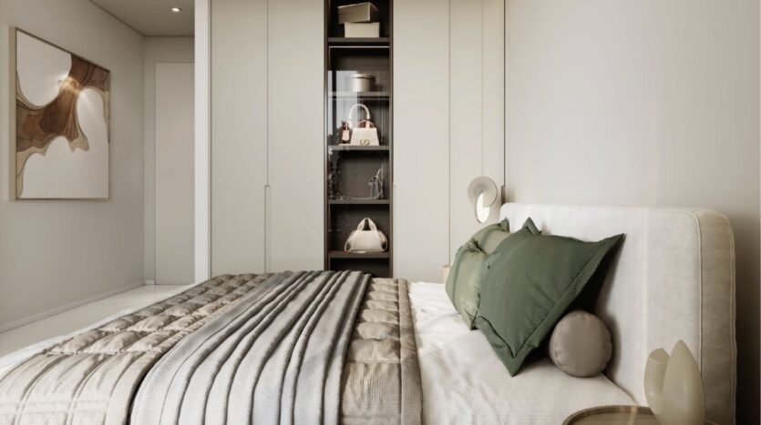 Une chambre à coucher moderne avec un lit soigneusement fait avec des oreillers verts et gris, une tête de lit rembourrée et une couette à rayures grises. Des placards encastrés et des étagères contenant des sacs et des objets de décoration évoquent le luxe de Franck Muller Yachting à Dubai Maritime City. Des œuvres d'art abstraites ornent le mur.