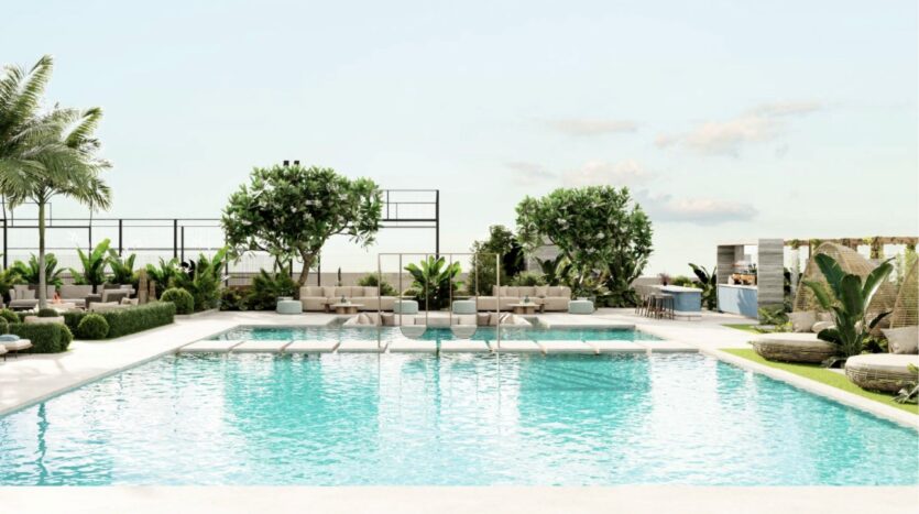 Une piscine extérieure luxueuse entourée de chaises longues, de palmiers et de verdure, avec une eau bleue claire et une atmosphère moderne et relaxante, idéale pour découvrir Franck Muller Yachting à Dubai Maritime City sous un ciel radieux.