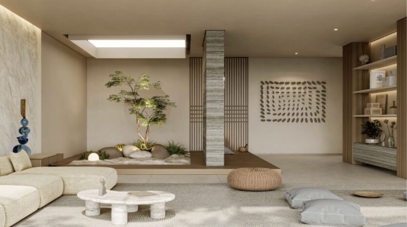 Un salon serein et minimaliste aux tons neutres est composé d'un canapé bas, d'une table basse ronde en pierre, de coussins de sol et d'œuvres d'art murales en pierre, reflétant l'élégance de Franck Muller Yachting à Dubai Maritime City grâce à son design paisible.