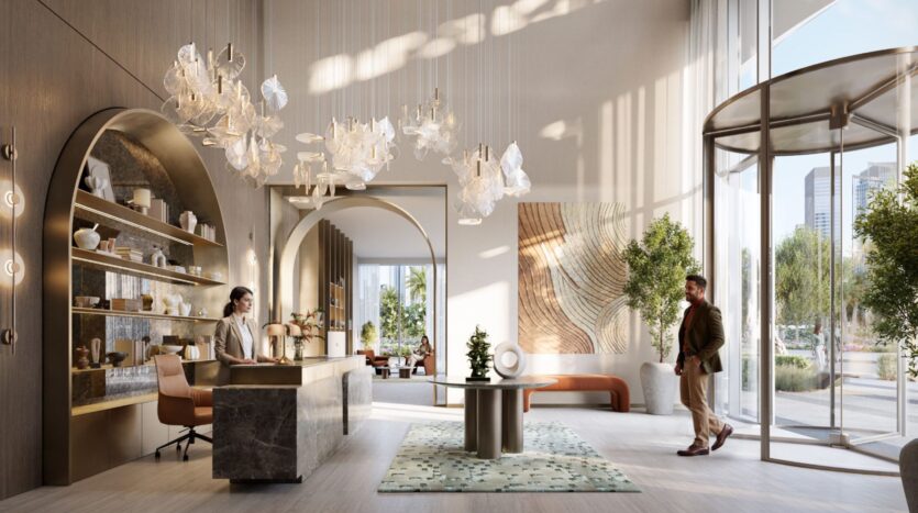 The lobby of the Hotel Avarra features high windows, a marble reception desk manned by a woman, artistic chandeliers, decorative shelving, green plants and a man entering through a revolving glass door.