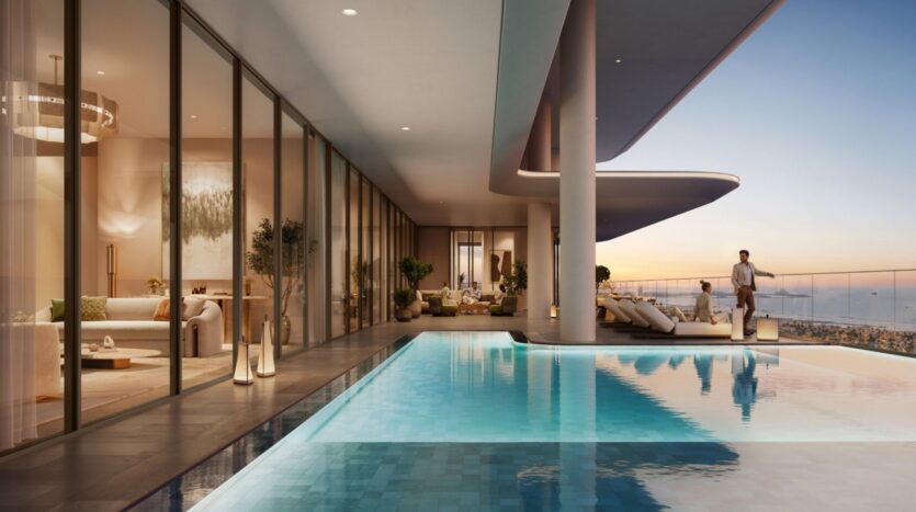 Modern luxury apartment in Avarra with floor-to-ceiling windows, spacious living room and infinity pool overlooking the cityscape at sunset. One person stands by the glass balustrade, enjoying the breathtaking view.