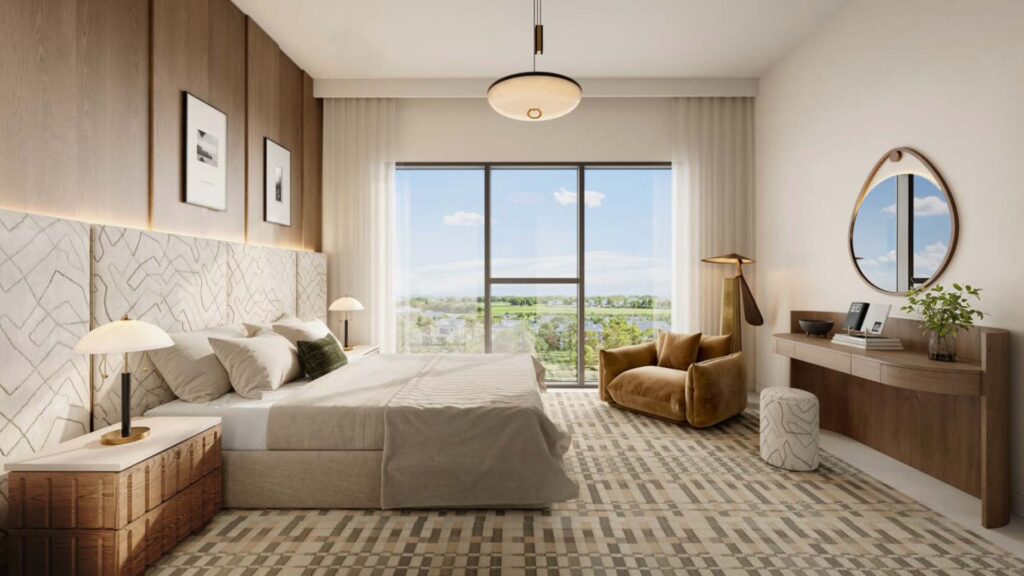 Camera da letto moderna con letto king-size, biancheria da letto neutra, accenti in legno, specchio rotondo, cassettiera, lampada e poltrona. La finestra a tutta altezza si affaccia sul verde di Golf Hills. Le luci soffuse e l'arredamento minimalista creano un'atmosfera confortevole.