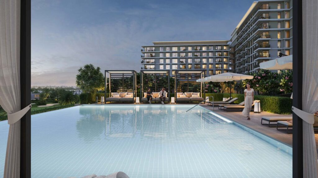 Lussuosa piscina all'aperto con lettini, ombrelloni e posti a sedere al Golf Hills. Persone che si rilassano a bordo piscina, con un moderno edificio a più piani sullo sfondo, sotto il cielo limpido della sera.