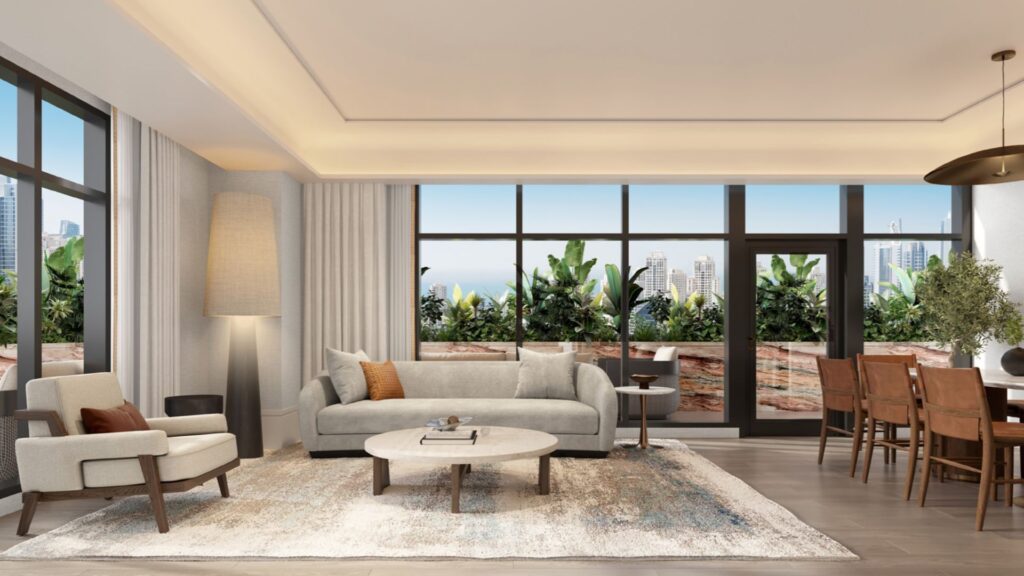 A modern living and dining room in Hilton Residences with large windows, neutral-toned furniture, a round coffee table, a tall lamp and views of city buildings and greenery from the balcony.