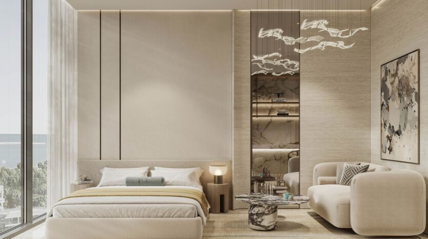 The modern, minimalist bedroom at Rabdan Gardens features neutral tones, a king-size bed, a cream sofa, abstract wall art, floor-to-ceiling windows with ocean views, and elegant ceiling-hung light fixtures.
