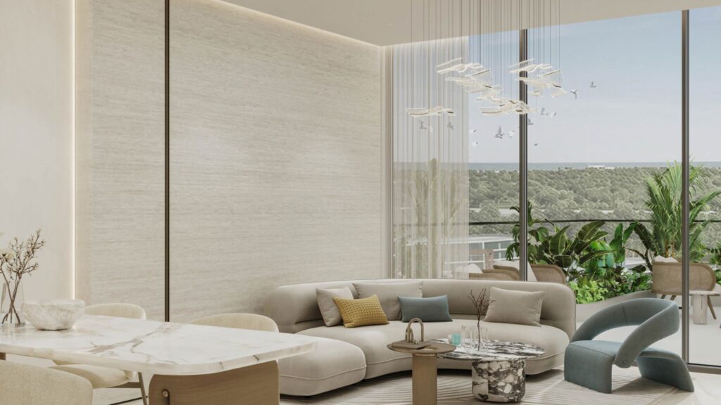 A modern living room in Rabdan Gardens with a curved beige sofa, marble dining table, contemporary chandelier, blue accent chair and large windows overlooking a balcony with green plants and panoramic views of the outdoors.