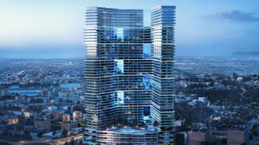 A modern building with glass facades and multiple terraces overlooks a sprawling cityscape at dusk, as the lights begin to appear in the city below.