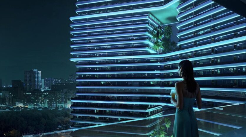 A woman in a blue dress stands on a balcony at night, gazing at a modern building with blue lights and Sky Terraces. City lights and trees sparkle in the background.