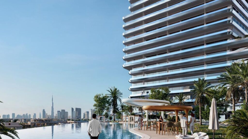 A person stands by an infinity pool with sun loungers, palm trees and parasols on elegant aerial terraces next to a modern high-rise building, with an urban skyline and a tall skyscraper visible in the background.