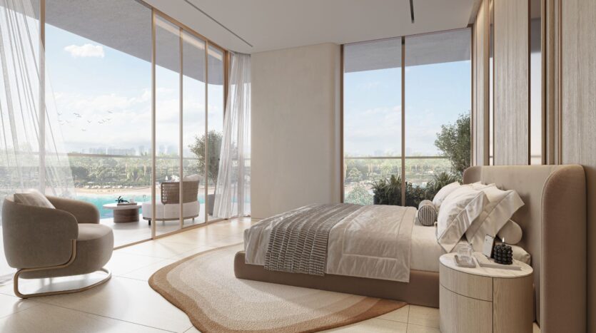 La soleggiata e moderna camera da letto di Le Caden è caratterizzata da vetrate a tutta altezza, una palette di colori neutri, un letto king-size e una comoda poltrona, che incorniciano la serena vista della piscina, della vegetazione lussureggiante e del cielo attraverso eleganti tende trasparenti.