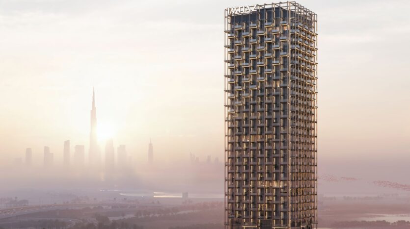A large modern skyscraper called The Symphony, with a unique lattice-shaped facade, stands out against the hazy skyline of a city at sunrise, with other skyscrapers visible in the distance.
