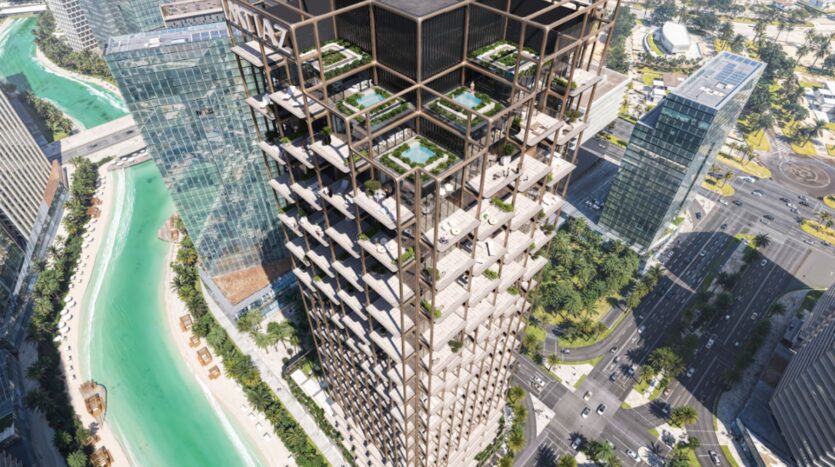 The Symphony, a tall modern tower with geometric balconies and rooftop terraces, overlooks a turquoise canal, city roads, and surrounding glass buildings in an elegant urban landscape.