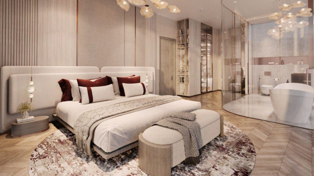 A modern, luxurious bedroom - The Symphony of Comfort - features a king-size bed with plush pillows and throws, a round-patterned rug, a bench seat at the foot of the bed, hanging lamps and an open bathroom with a freestanding bathtub.