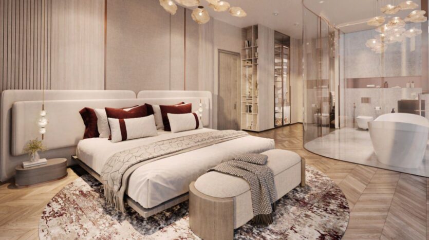 A modern, luxurious bedroom - The Symphony of Comfort - features a king-size bed with plush pillows and throws, a round-patterned rug, a bench seat at the foot of the bed, hanging lamps and an open bathroom with a freestanding bathtub.